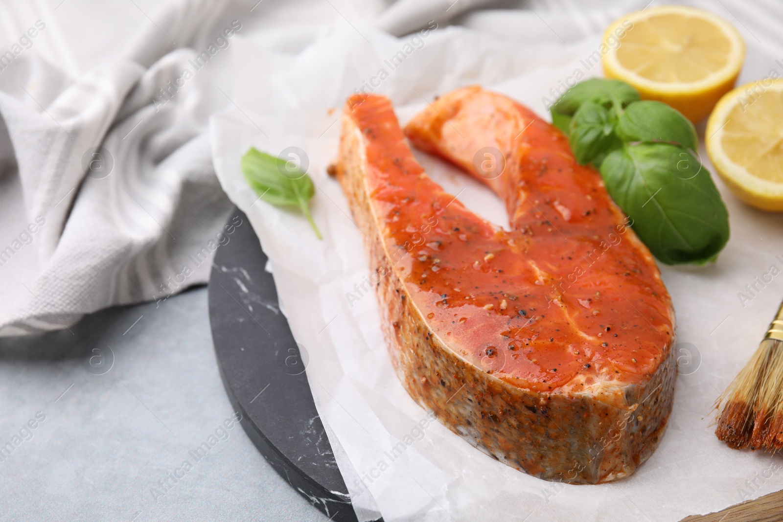 Photo of Fresh marinade, fish, lemon and basil on grey table, closeup