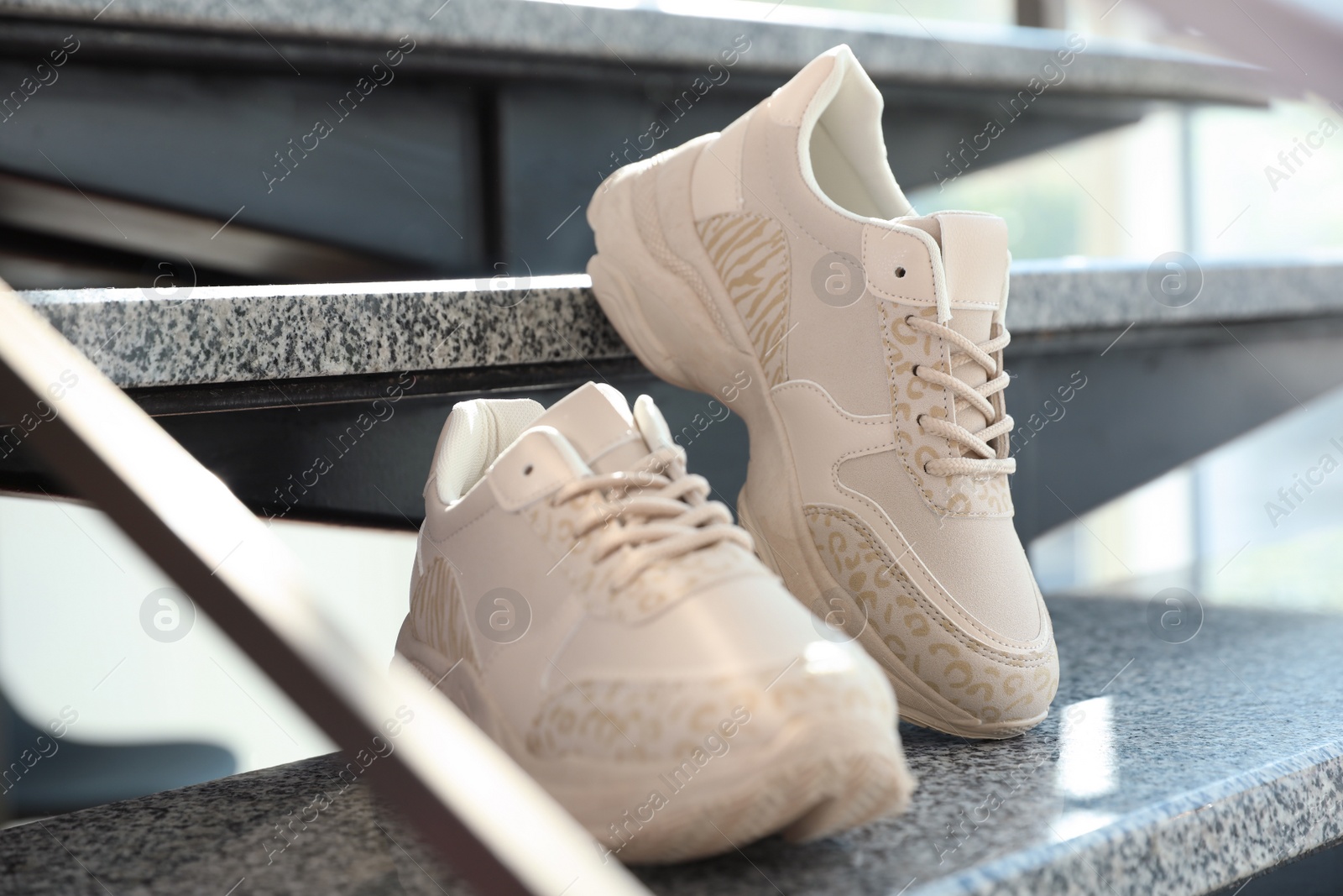 Photo of Pair of stylish women's sneakers on grey marble stairs indoors