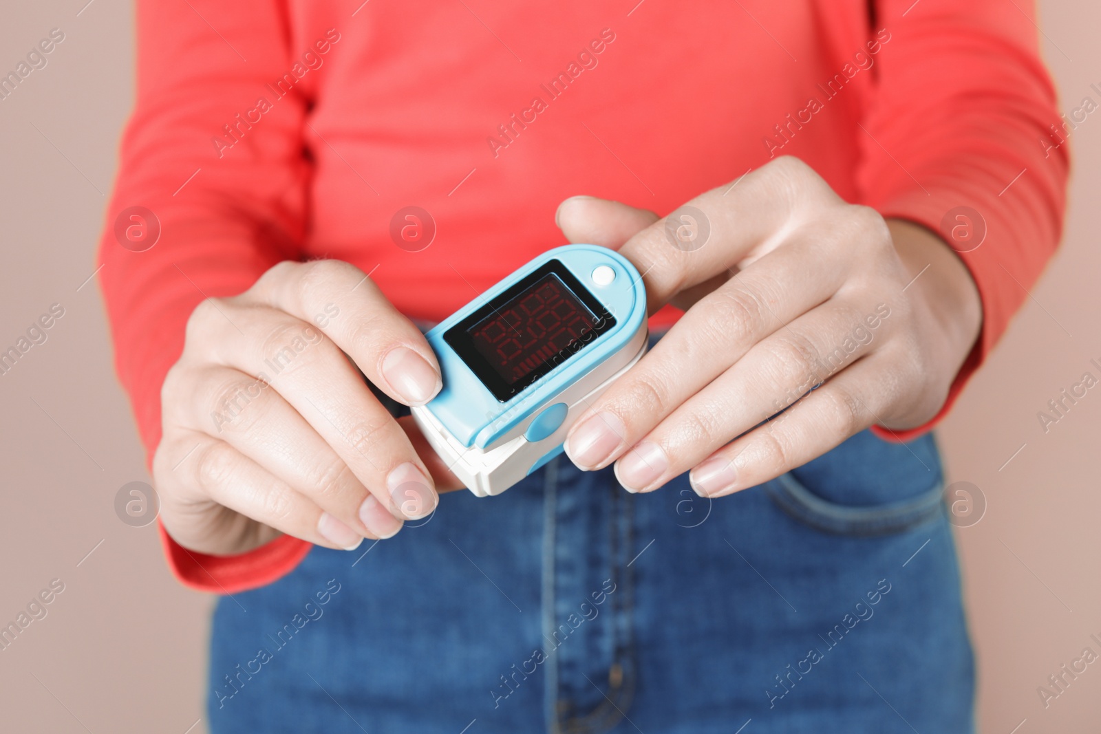Photo of Young woman checking pulse with digital medical device on color background, closeup