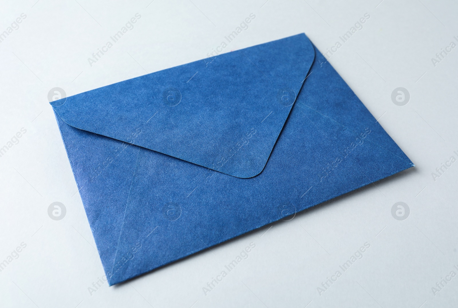 Photo of Blue paper envelope on light background, closeup. Mail service