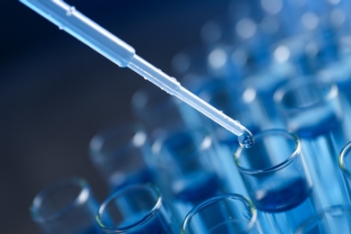 Photo of Dripping reagent into test tube with liquid sample on blurred background, closeup. Laboratory analysis