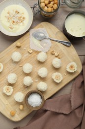 Photo of Delicious candies with coconut flakes, hazelnut and ingredients on wooden table, flat lay
