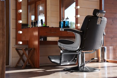 Photo of Stylish hairdresser's workplace with professional armchair and beautiful big mirror in barbershop