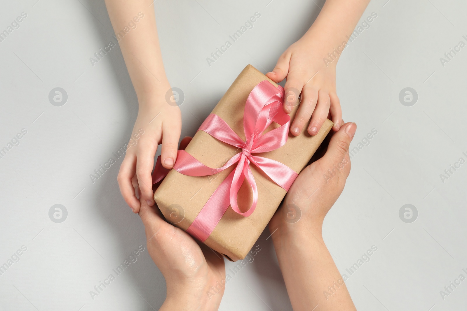 Photo of Mother and her child holding gift box on light gray background, top view