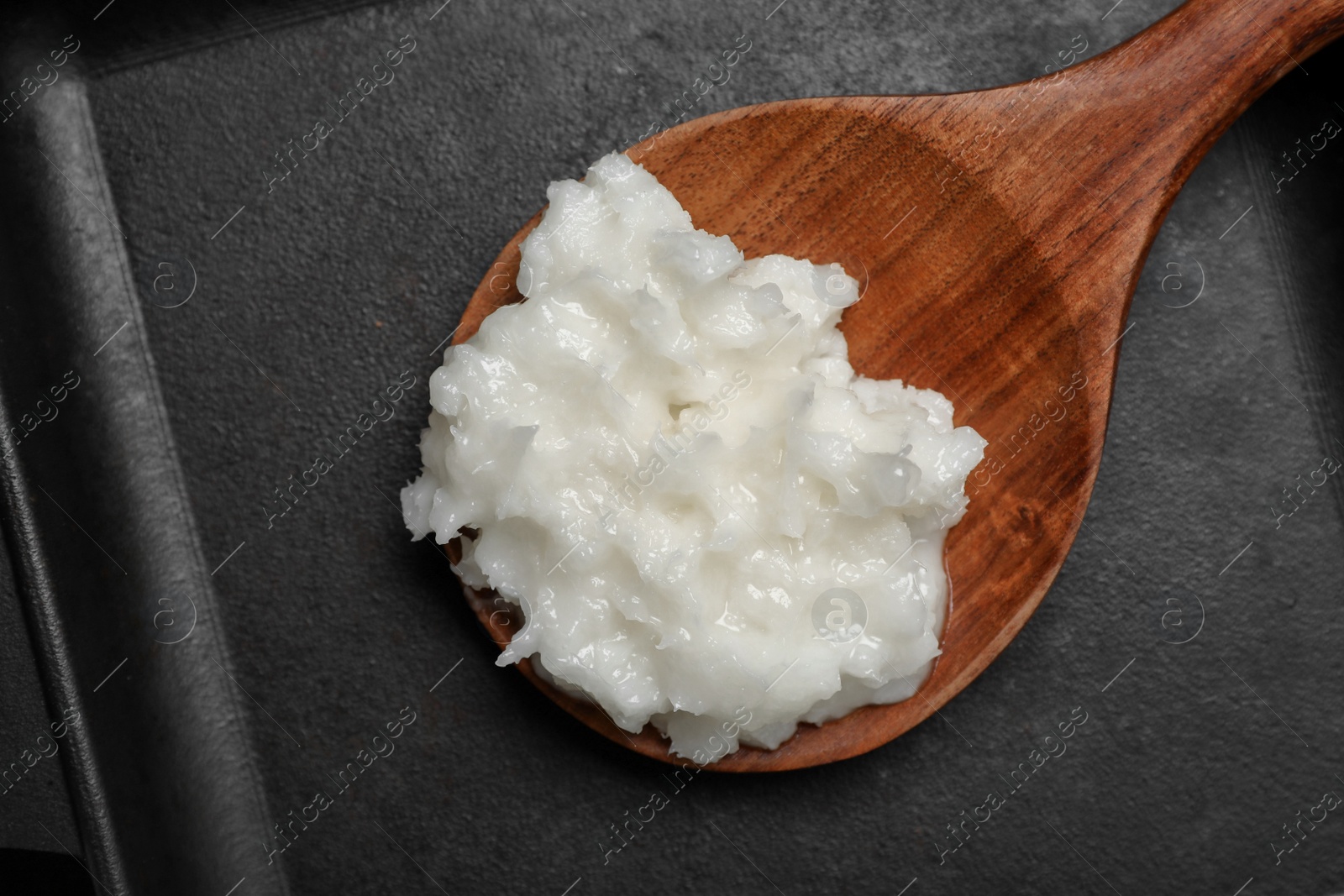 Photo of Baking dish with coconut oil and wooden spoon, top view