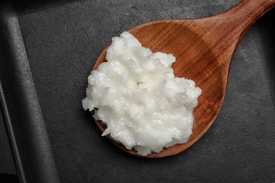 Baking dish with coconut oil and wooden spoon, top view