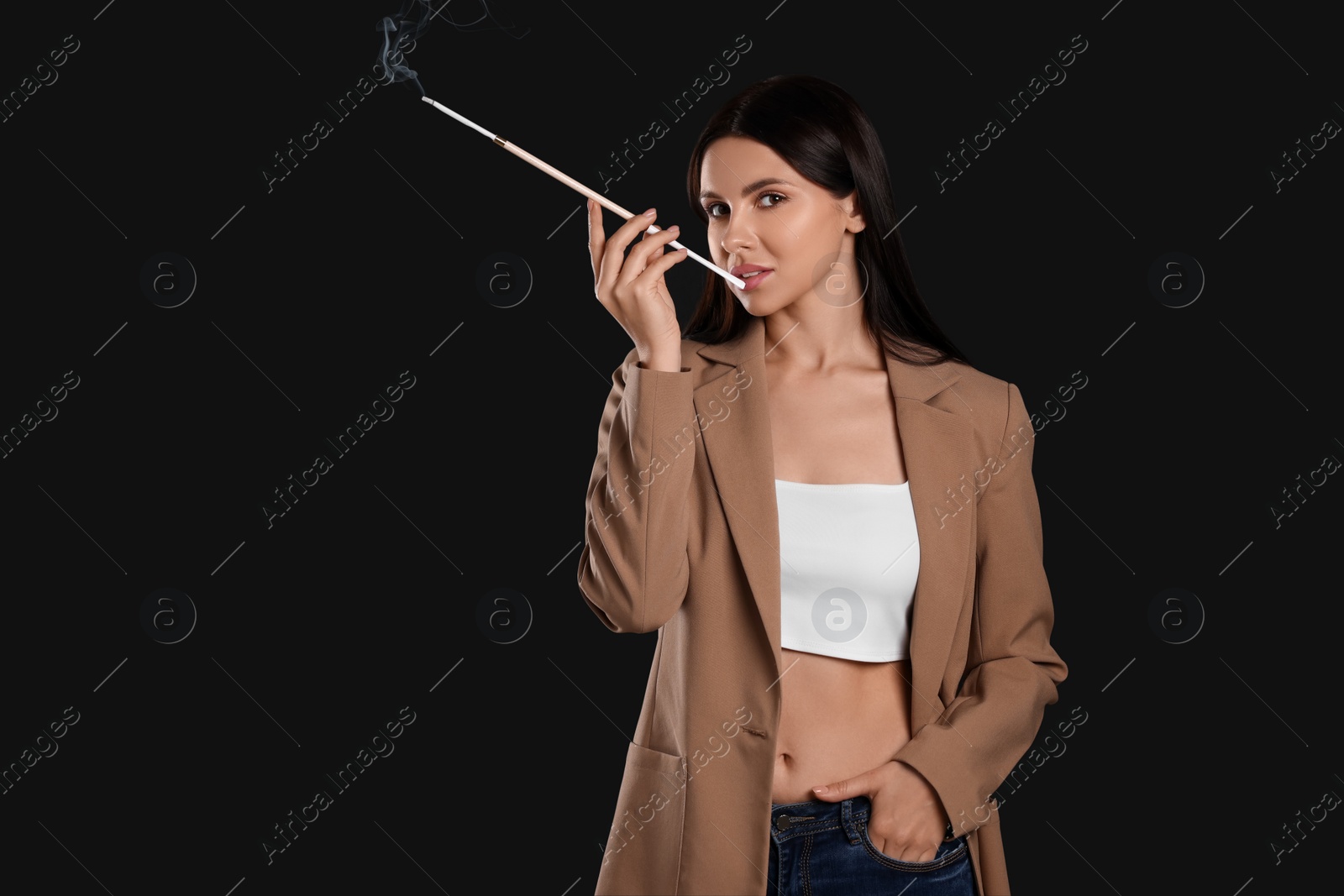 Photo of Woman using long cigarette holder for smoking on black background, space for text