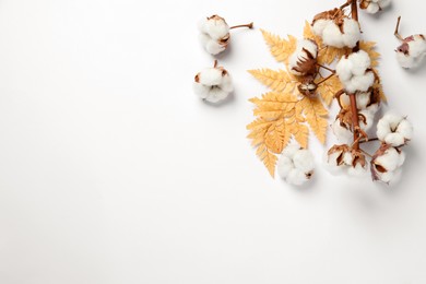 Photo of Fluffy cotton flowers and decorative leaf on white background, flat lay. Space for text