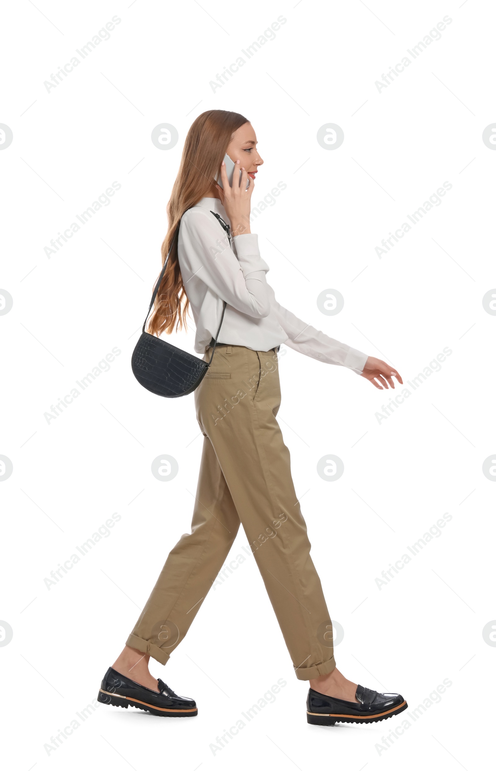 Photo of Young woman talking on smartphone while walking against white background