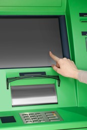 Photo of Woman using modern green cash machine, closeup