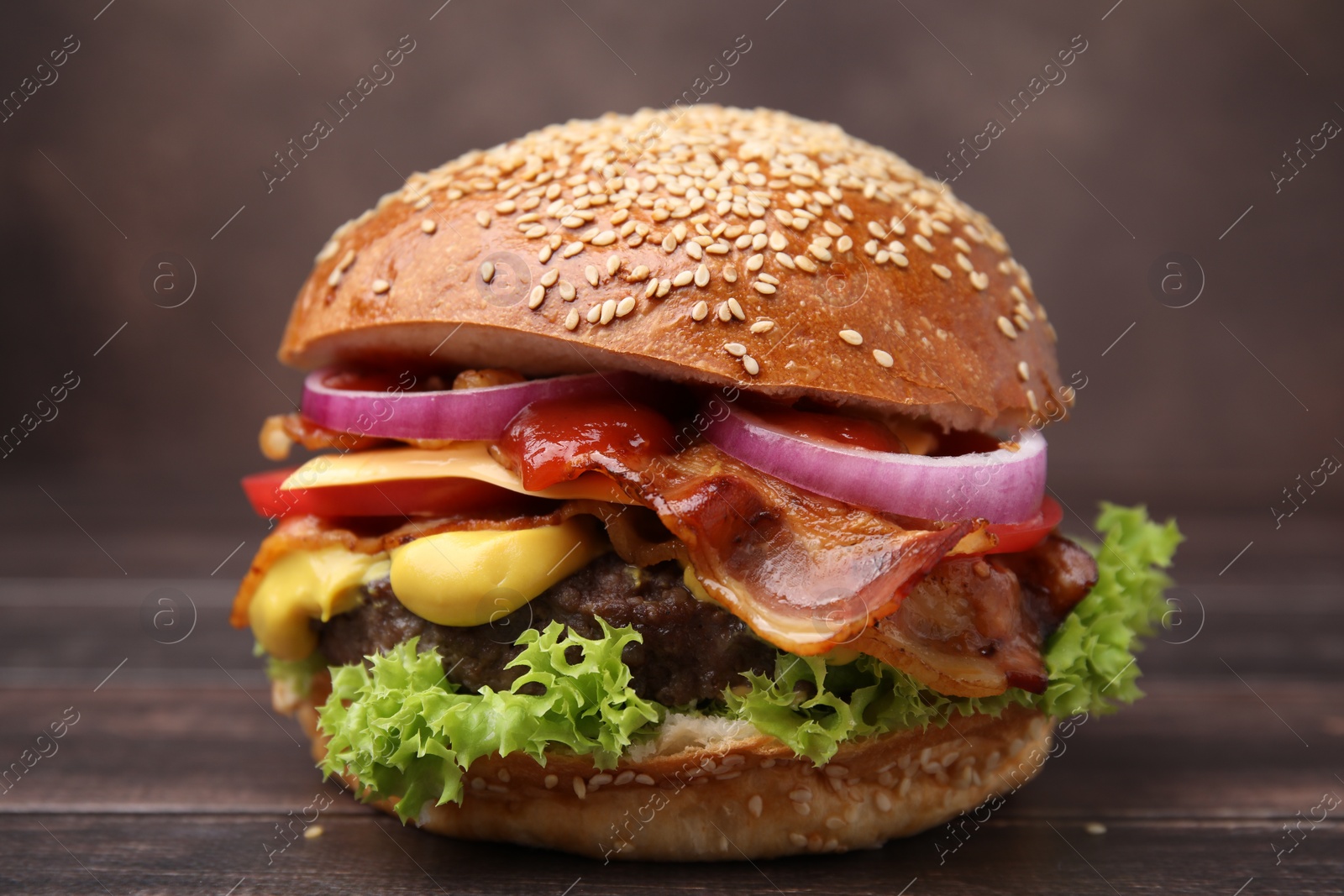 Photo of Delicious burger with bacon, patty and vegetables on wooden table, closeup