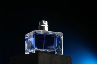 Luxury men`s perfume in bottle against dark background, low angle view. Space for text