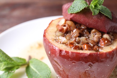 Photo of Tasty baked apple with nuts, honey and mint on table, closeup