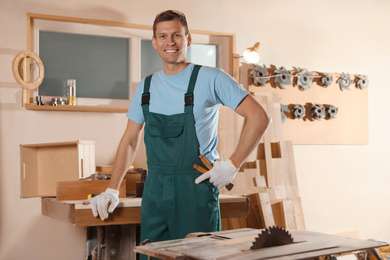 Photo of Professional carpenter in uniform near wooden workbench