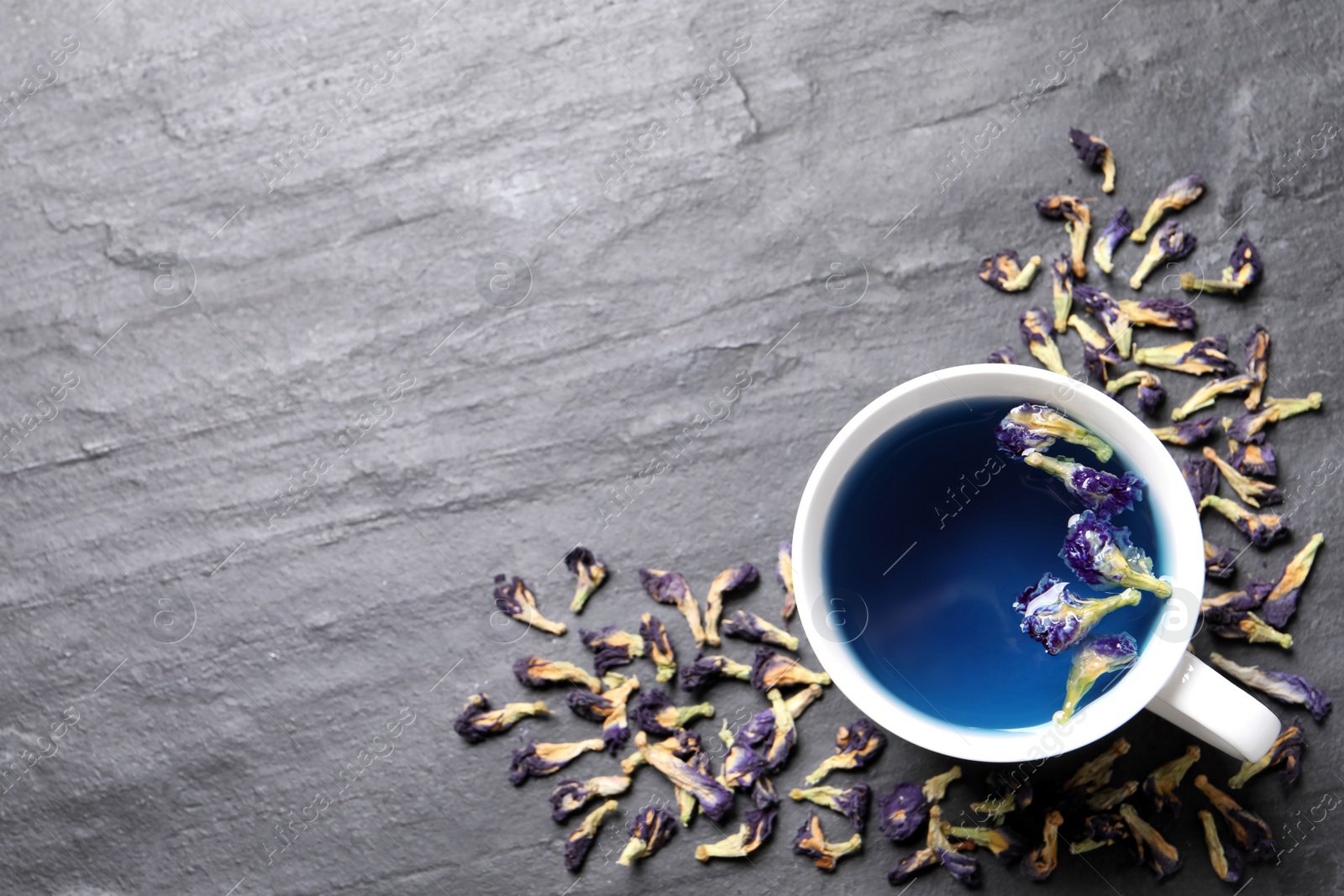 Photo of Organic blue Anchan in cup on grey table, flat lay with space for text. Herbal tea