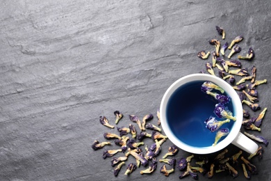 Photo of Organic blue Anchan in cup on grey table, flat lay with space for text. Herbal tea