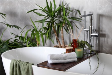 Photo of Modern white tub and beautiful green houseplants in bathroom. Interior design