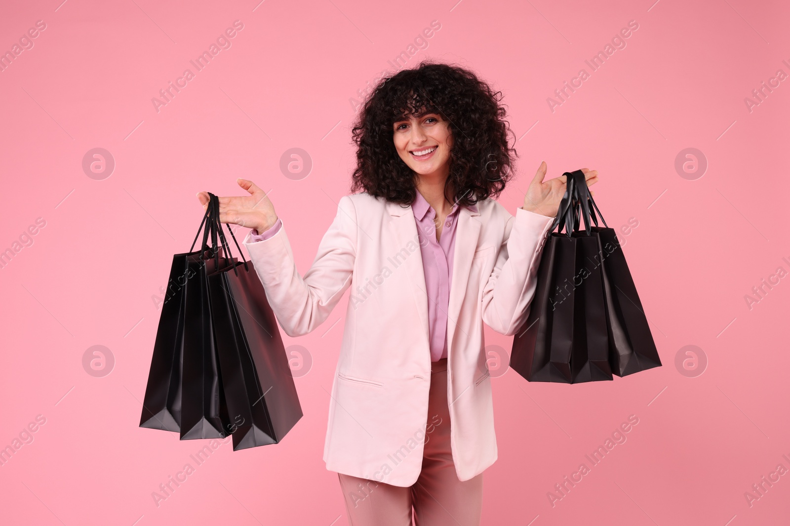 Photo of Happy young woman with shopping bags on pink background