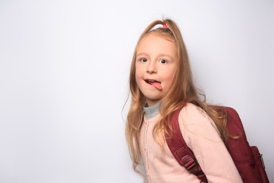 Photo of Emotional little girl with backpack on white background. Space for text