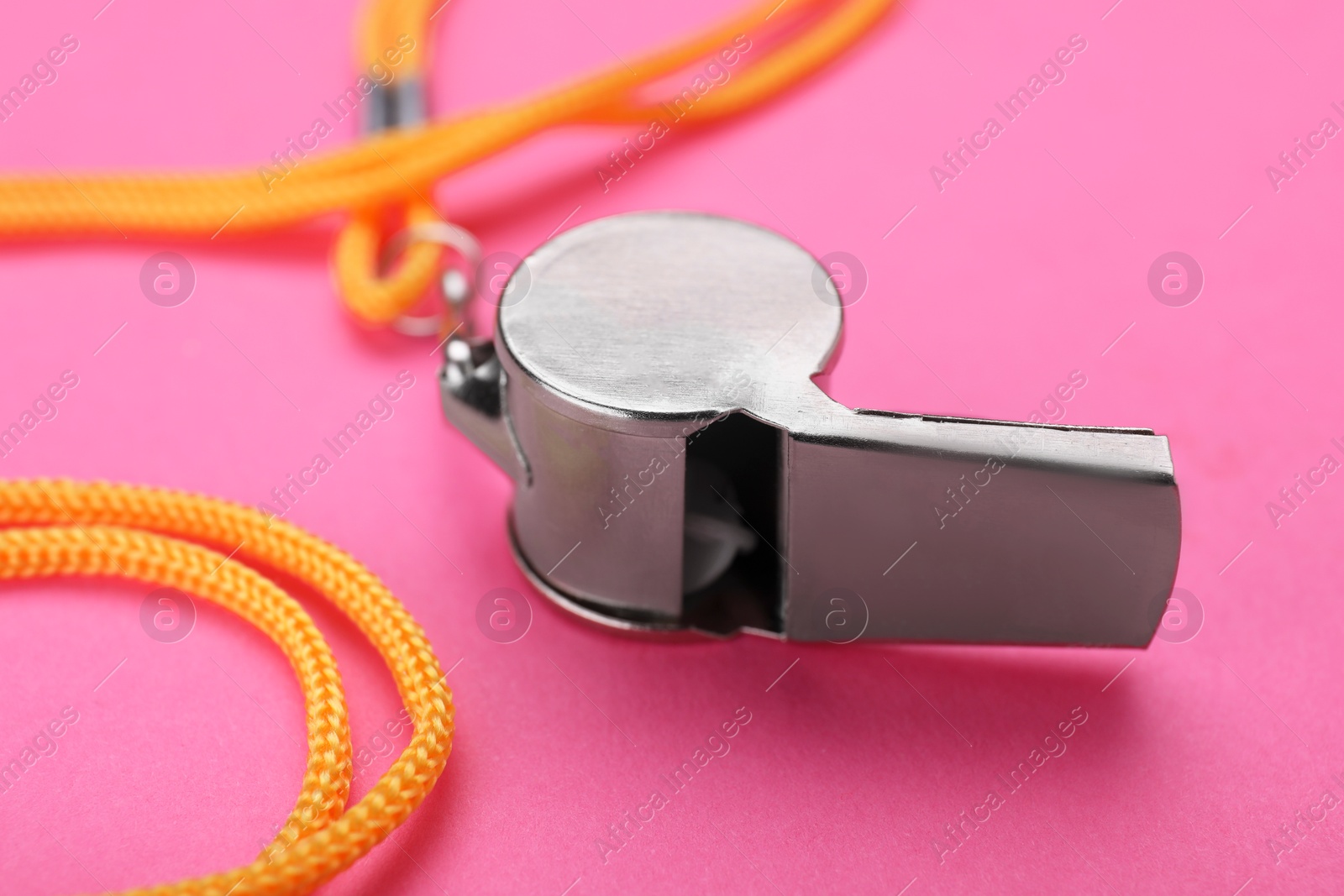 Photo of One metal whistle with cord on pink background, closeup
