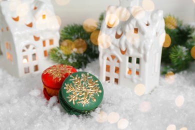 Different decorated Christmas macarons on table with artificial snow, space for text