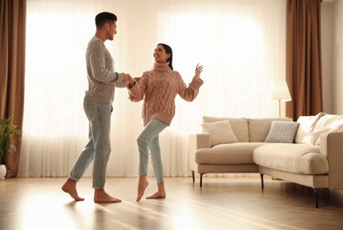 Photo of Happy couple dancing barefoot in living room. Floor heating system