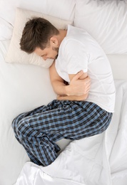 Photo of Man suffering from abdominal pain in bedroom