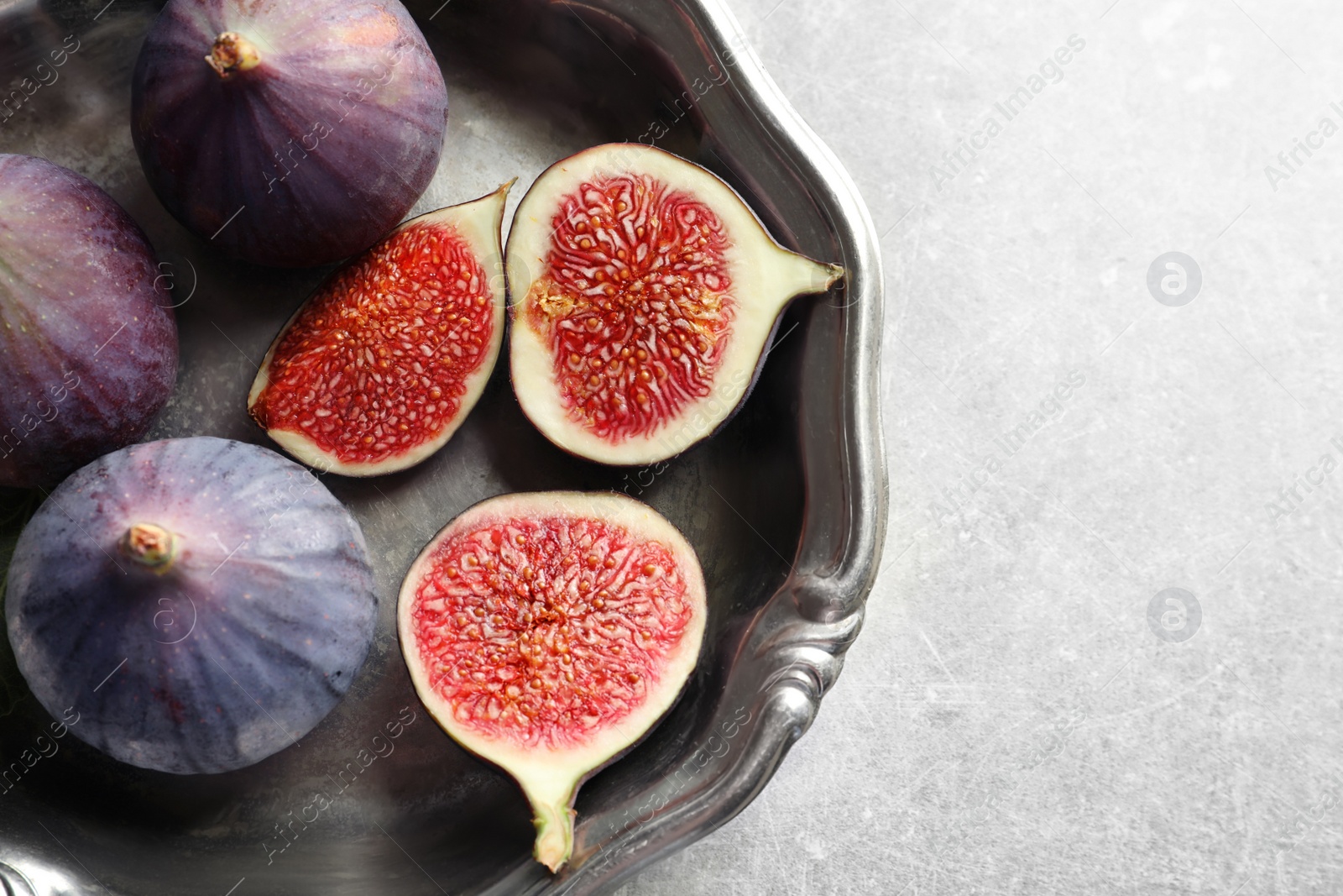 Photo of Dish with fresh ripe figs on gray background, top view. Space for text