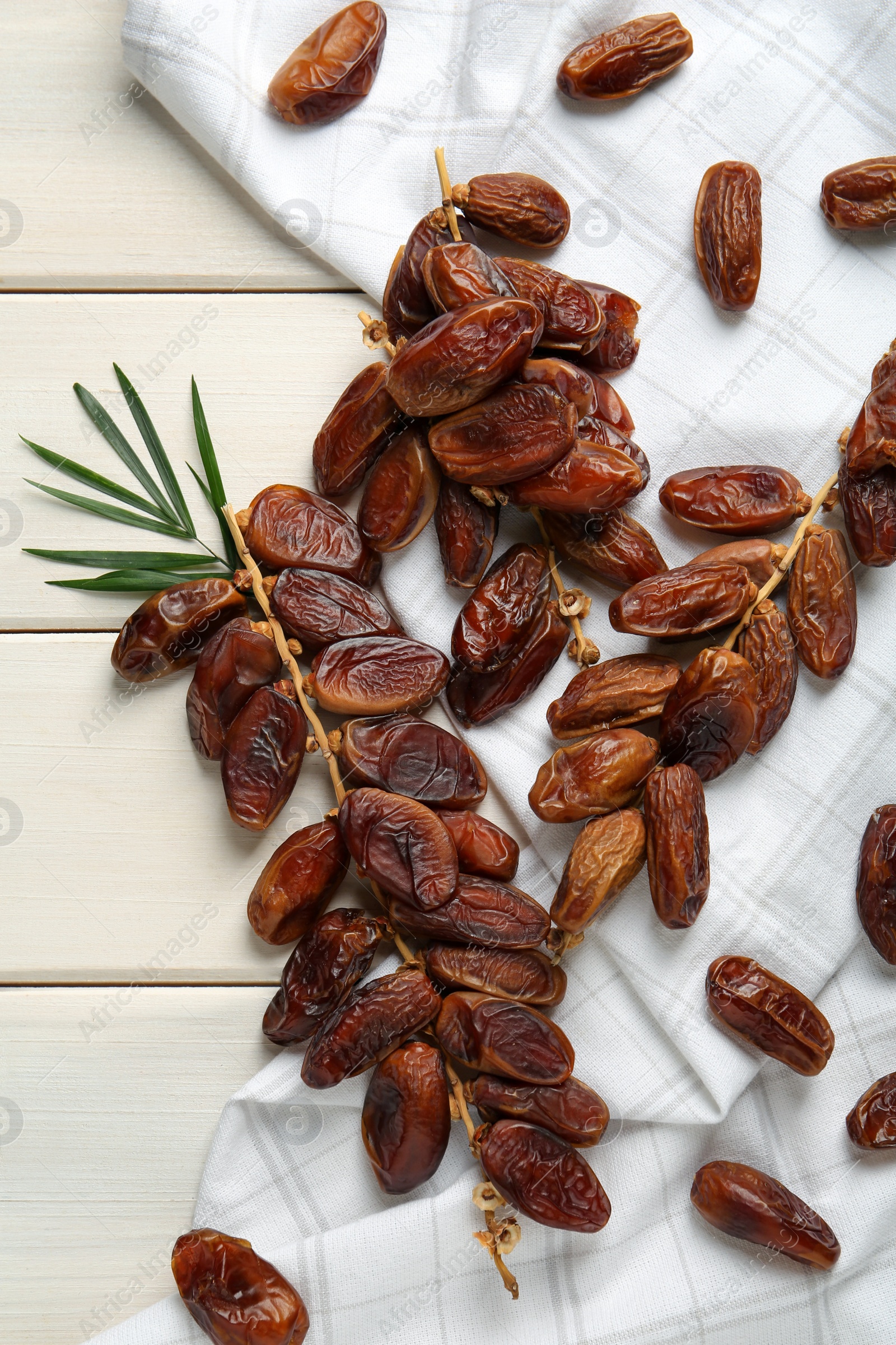 Photo of Tasty sweet dried dates and green leaf on white wooden table, flat lay