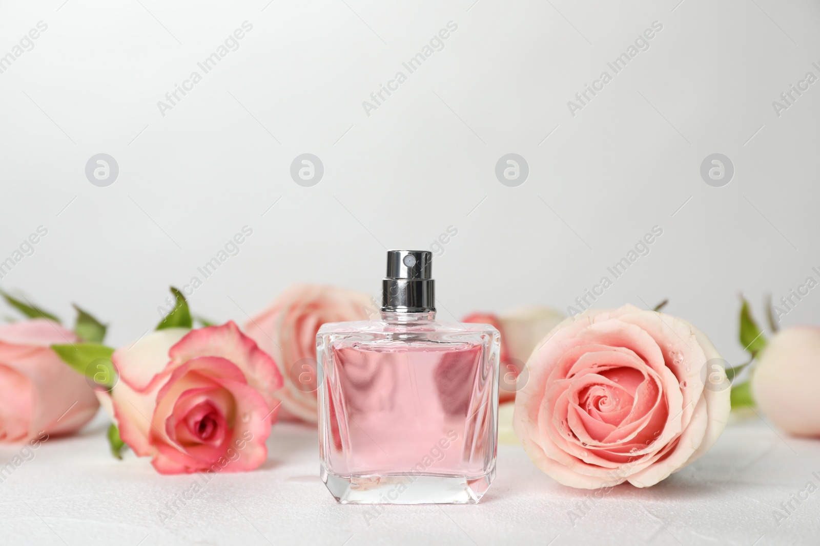 Photo of Perfume bottle and flowers on table against light background