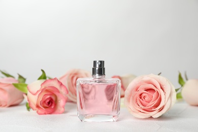 Photo of Perfume bottle and flowers on table against light background