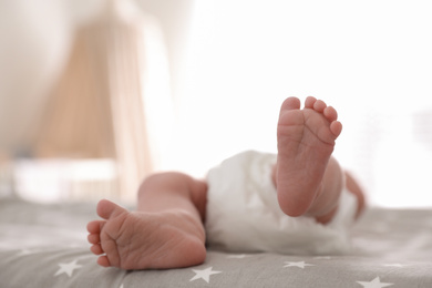 Photo of Cute little baby lying on bed at home, closeup of legs
