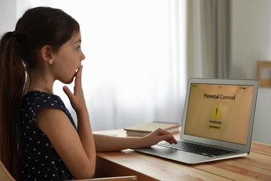Photo of Child using laptop with installed parental control app at home. Cyber safety