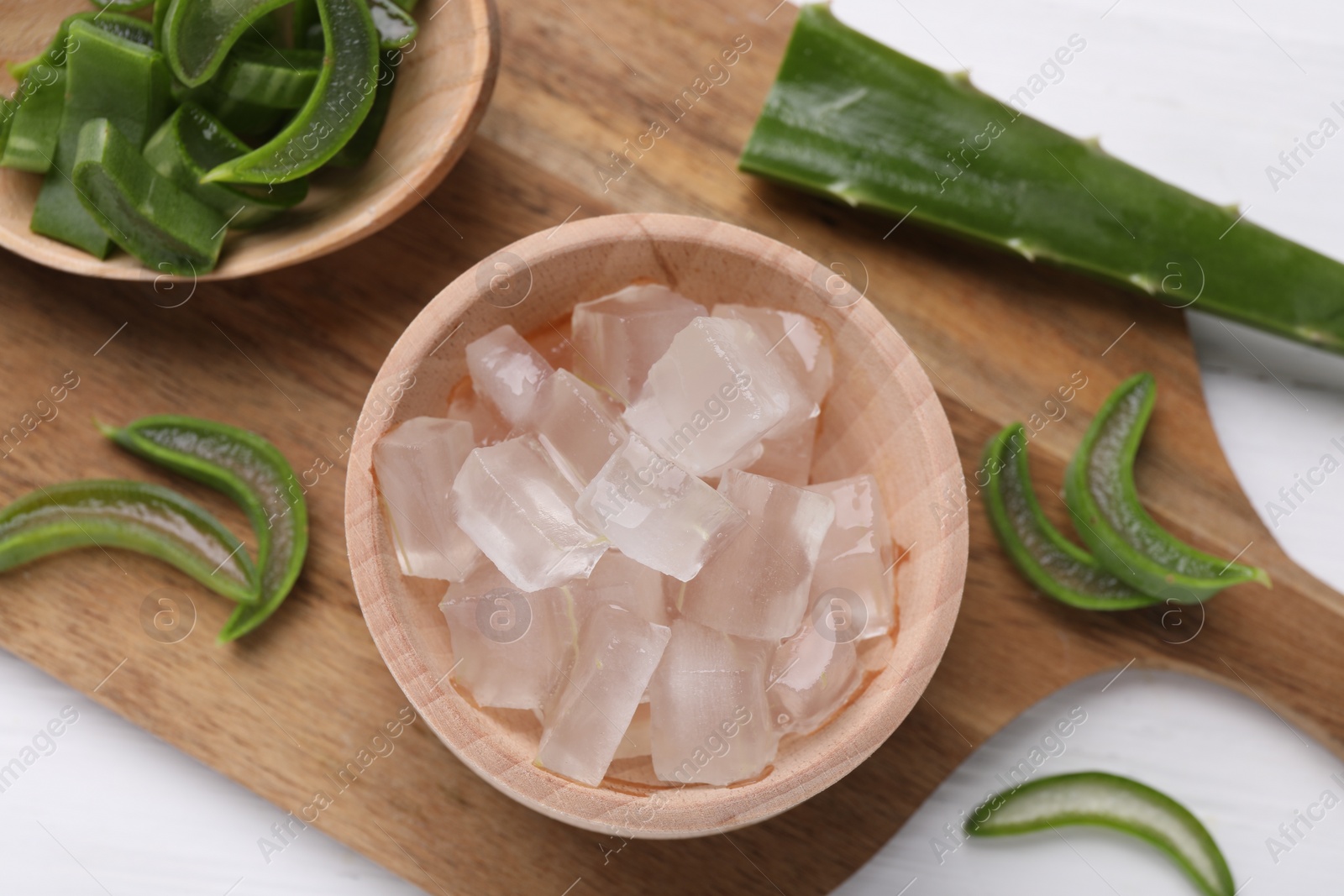 Photo of Aloe vera gel and slices of plant on white background, top view