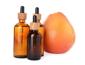 Photo of Bottles of citrus essential oil and fresh grapefruit isolated on white