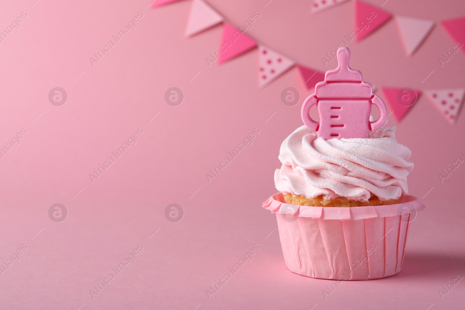 Photo of Beautifully decorated baby shower cupcake with cream and girl topper on pink background. Space for text