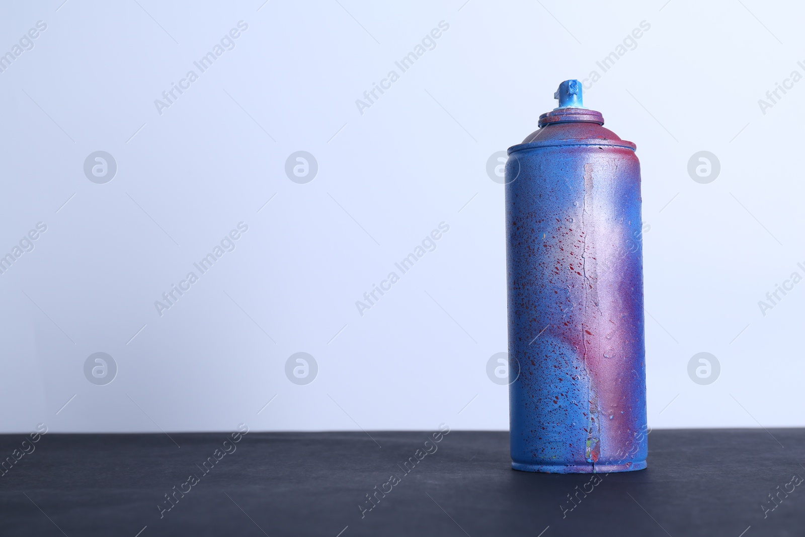 Photo of Spray paint can on black surface against white background, space for text