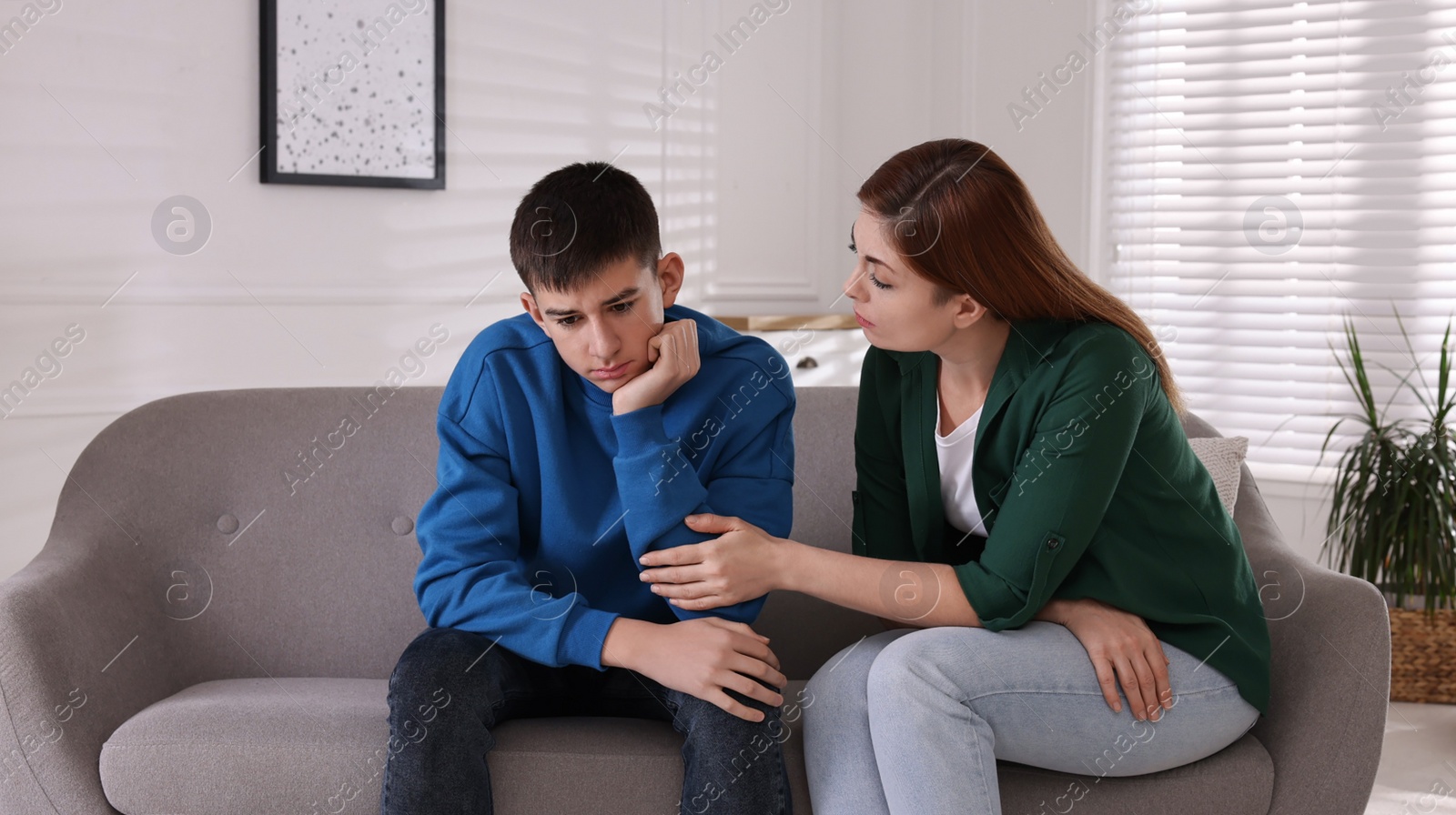 Photo of Mother consoling her depressed son at home. Teenager problems