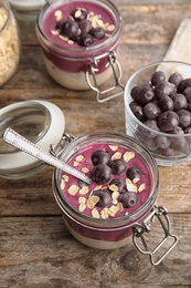 Photo of Jars with tasty acai smoothie on wooden table