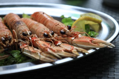 Plate with tasty boiled crayfish and salad on black table, closeup