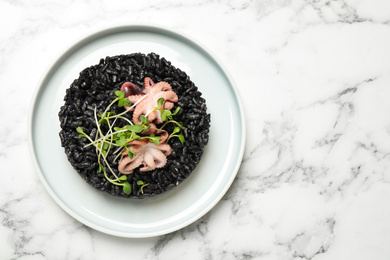 Photo of Delicious black risotto with seafood on white marble table, top view. Space for text
