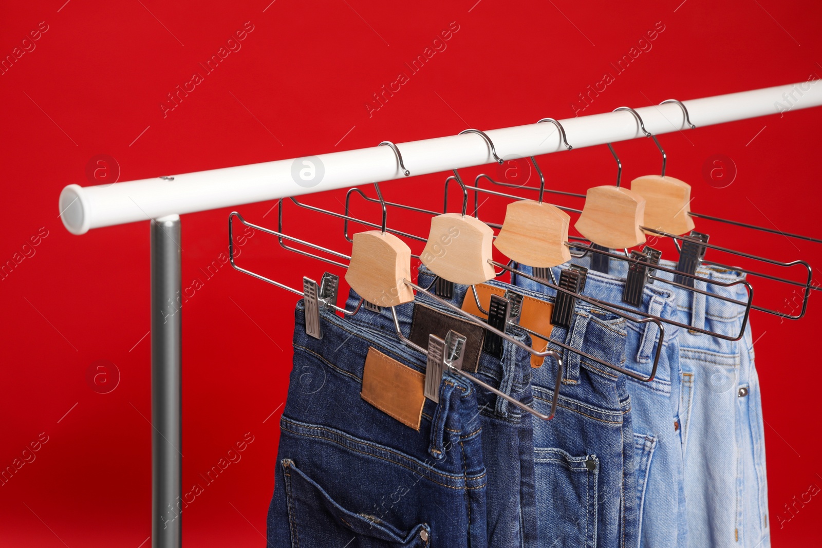 Photo of Rack with different jeans on red background