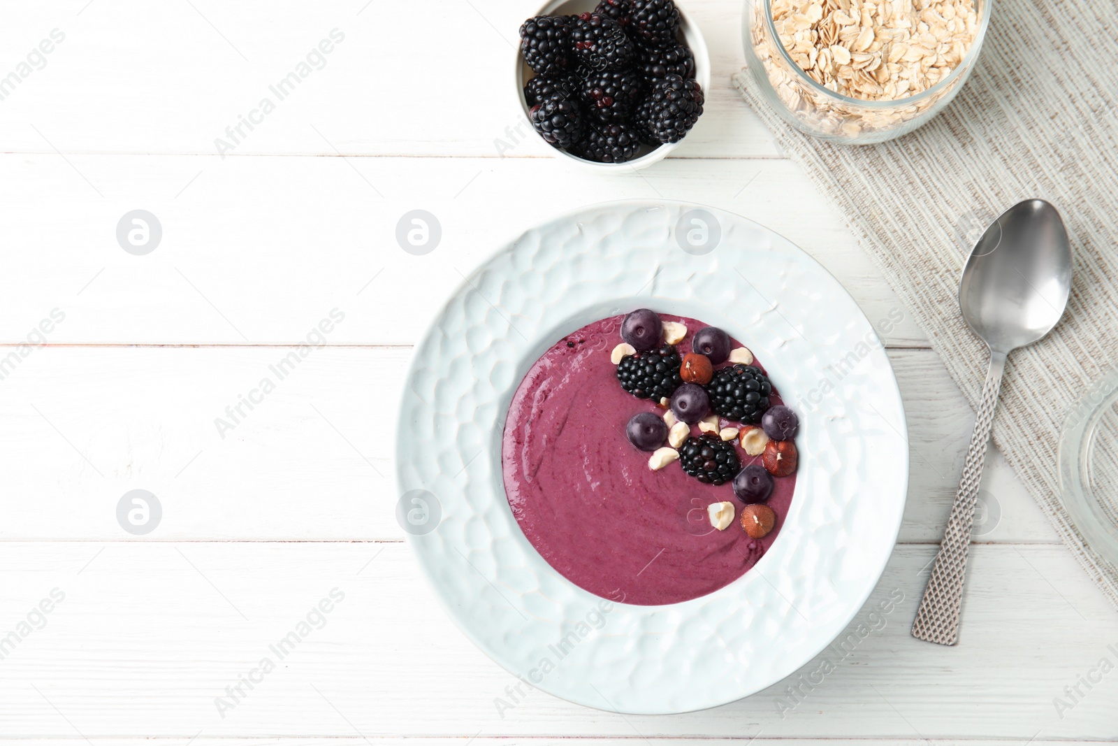 Photo of Flat lay composition with plate of tasty acai smoothie on wooden table