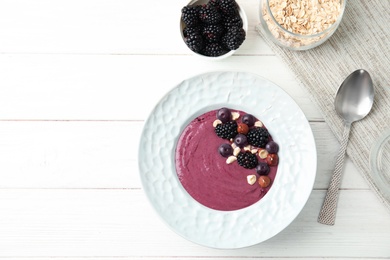 Flat lay composition with plate of tasty acai smoothie on wooden table