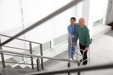 Photo of Nurse assisting senior man with walker in hospital