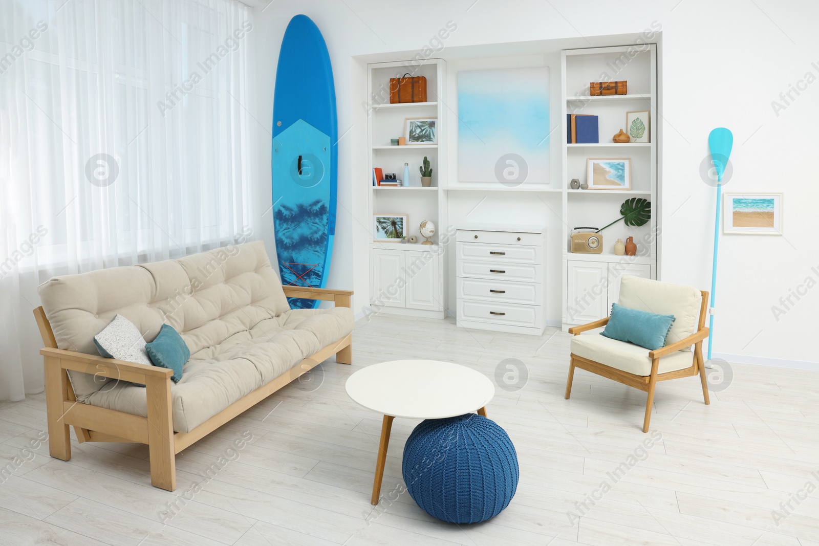 Photo of SUP board and modern furniture in stylish living room. Interior design