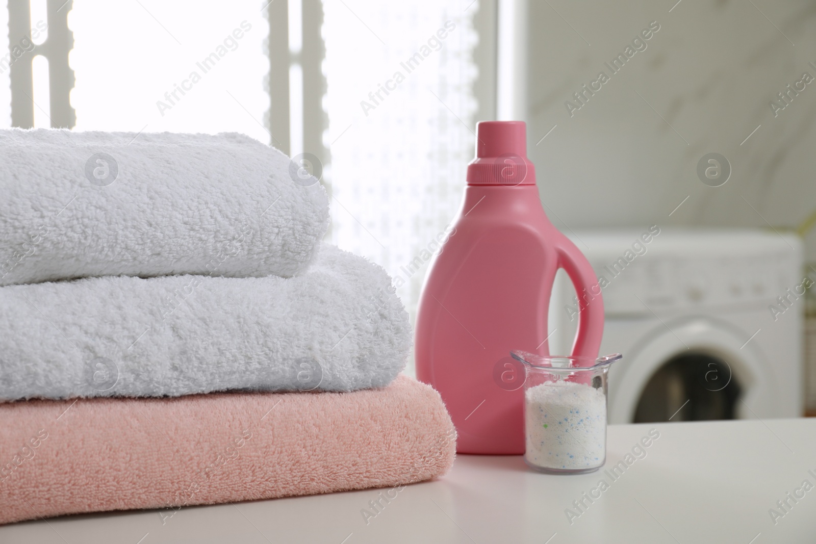 Photo of Clean towels and detergents on table in laundry room