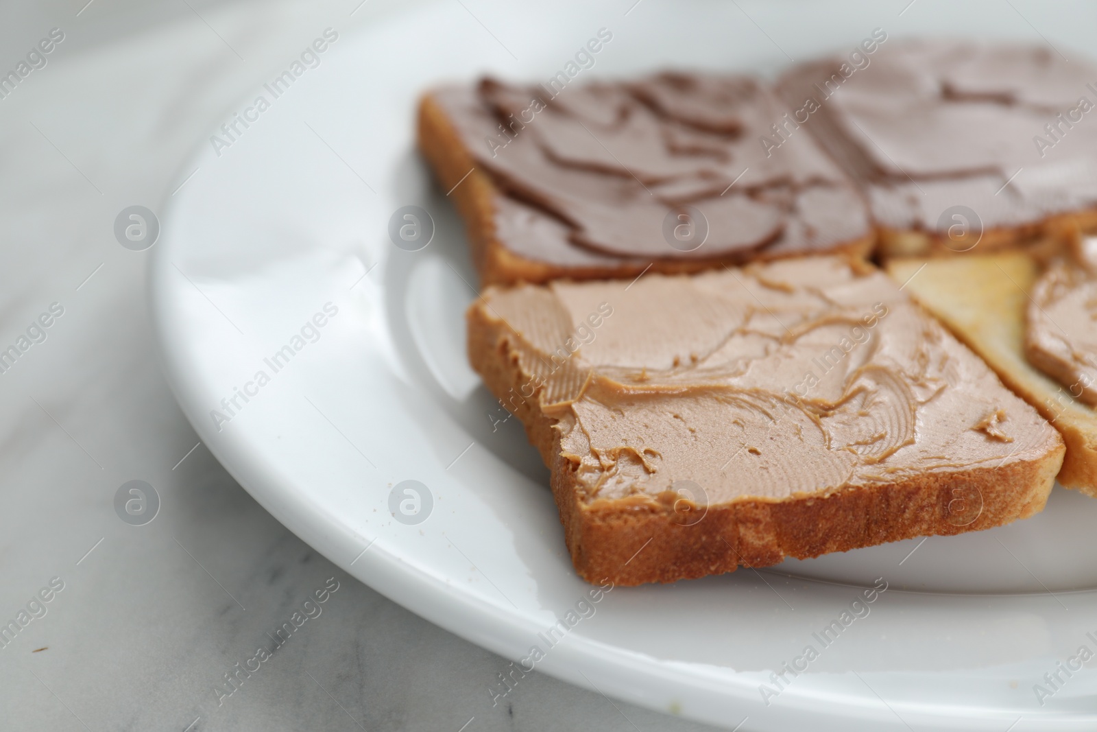 Photo of Toasts with tasty nut butter on marble table, closeup