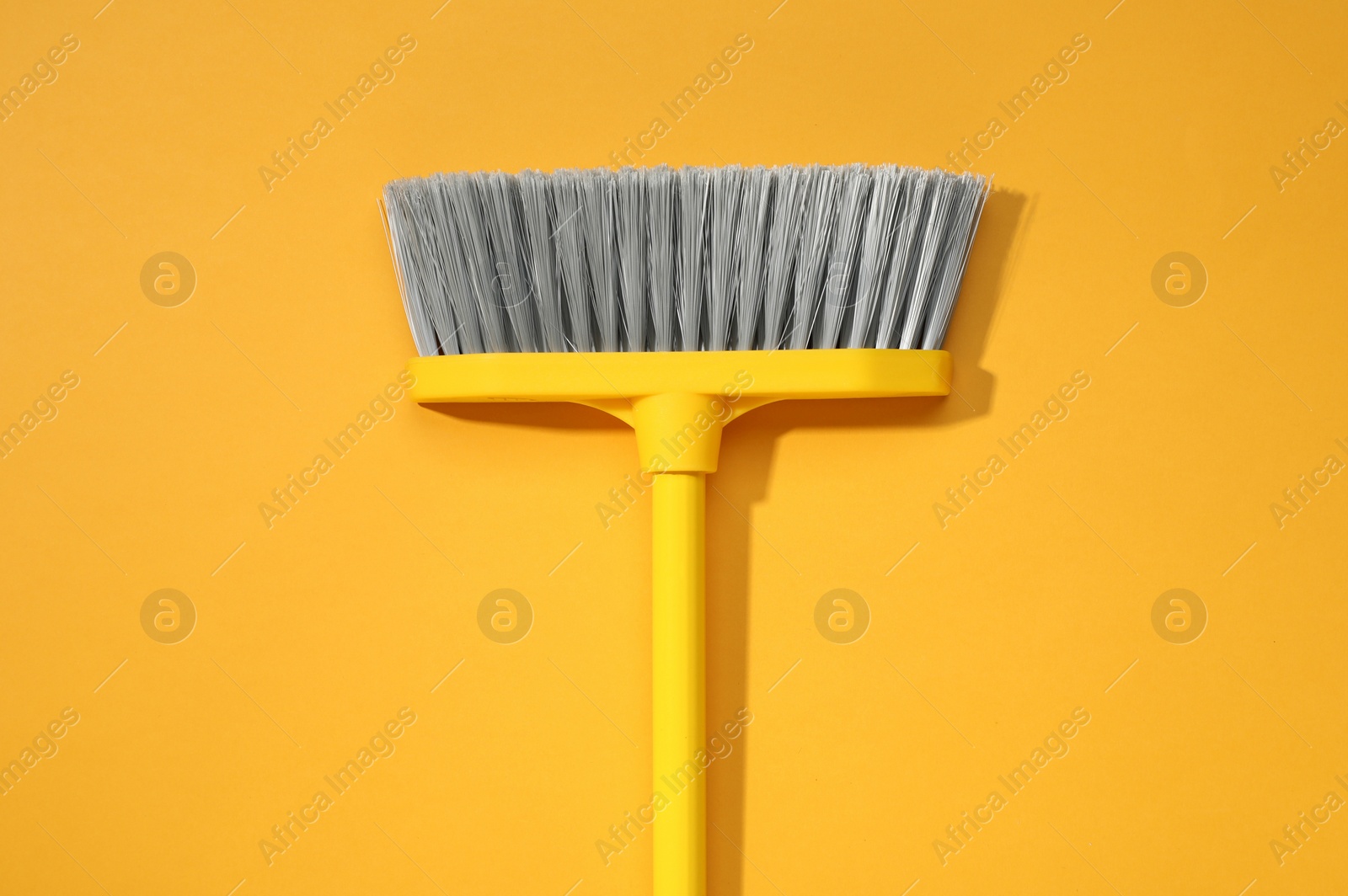 Photo of Plastic broom on yellow background, top view