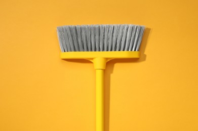 Photo of Plastic broom on yellow background, top view